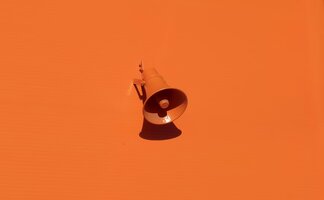 Ein orangenes Megaphon auf orangem Hintergrund.
